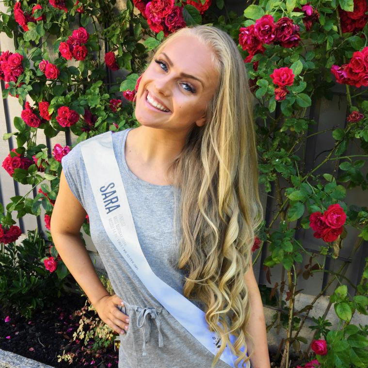 Sara Hassing med navne-sash og roser i bakgrunnen